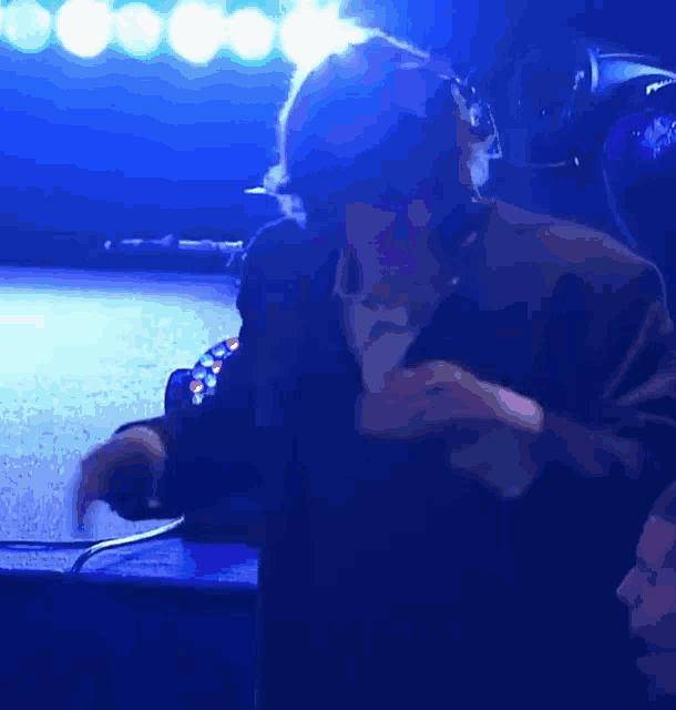 a man wearing headphones is dancing on a stage with blue lights behind him