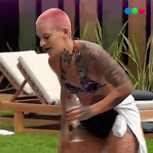a woman in a bikini is standing on a lawn chair holding a glass of wine