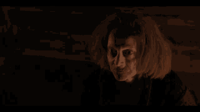 a man is standing in the dark in a dark room looking at the camera .