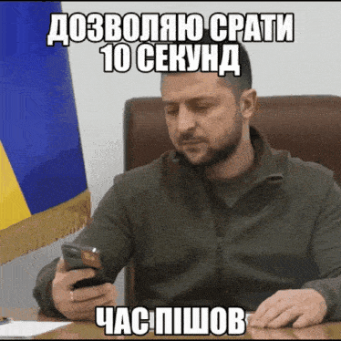a man is sitting at a desk looking at his phone with a foreign language caption above him