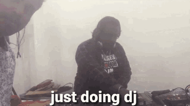 a man wearing headphones and a shirt that says " just doing dj "