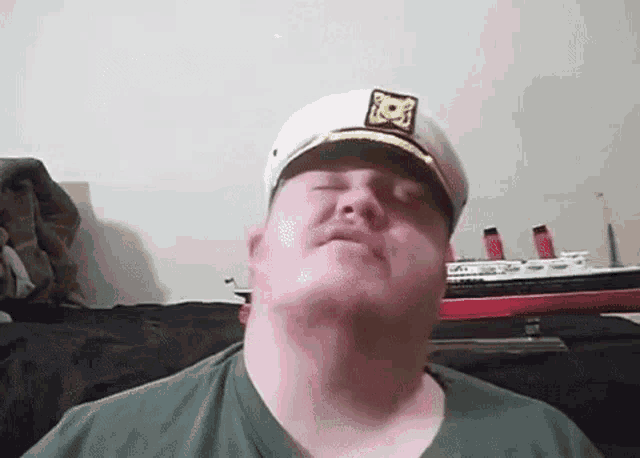 a man wearing a captain 's hat looks down at something
