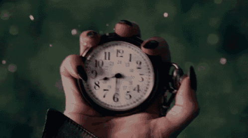 a woman is holding a pocket watch in her hand which shows the time as 5:05