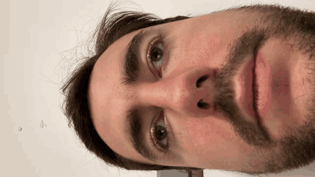 a man with a beard and blue eyes looks down at the camera