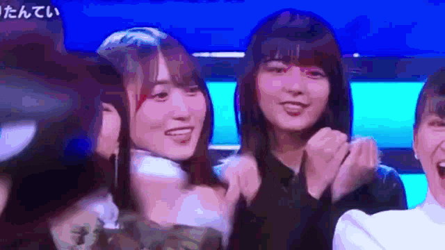 a group of young women are standing next to each other and laughing .