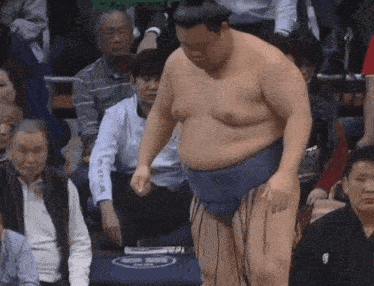 a sumo wrestler is standing in front of a crowd while wearing a white shirt that says ' akira '