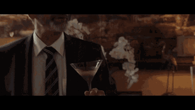 a group of people are gathered in a living room and one man is holding a martini