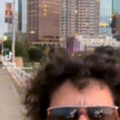 a man wearing sunglasses is standing in front of a city skyline