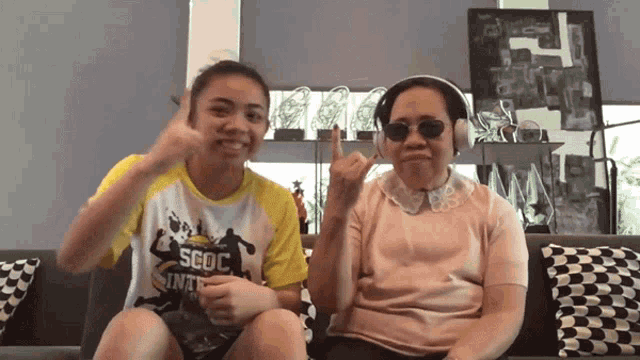 a girl wearing a shirt that says scoc is sitting next to an older woman