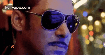 a close up of a man wearing sunglasses and looking at the camera .