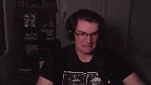 a man wearing glasses and headphones is sitting in front of a microphone and making a funny face .