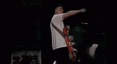 a man is playing a guitar on a stage with a drummer in the background