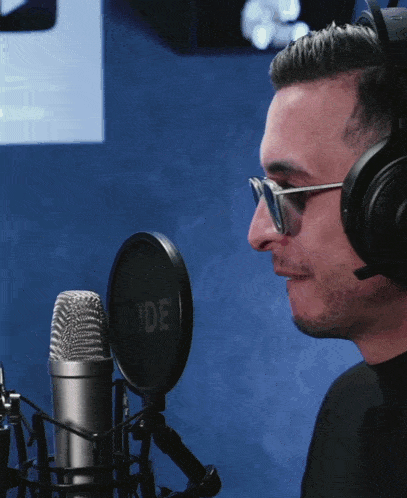 a man singing into a rode microphone with sunglasses on