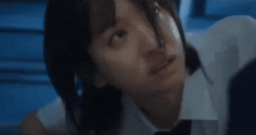 a close up of a person 's face with a blue background and a white shirt and tie .