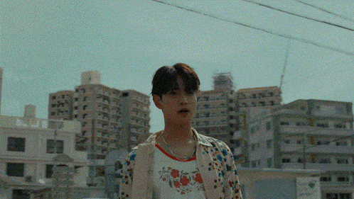 a man wearing a floral shirt stands in front of a city skyline
