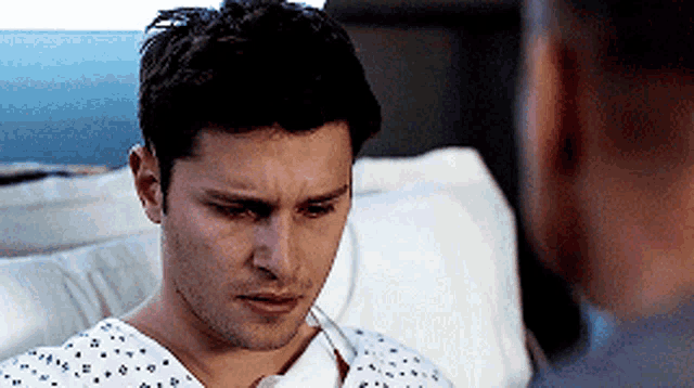 a man in a hospital gown is talking to another man .