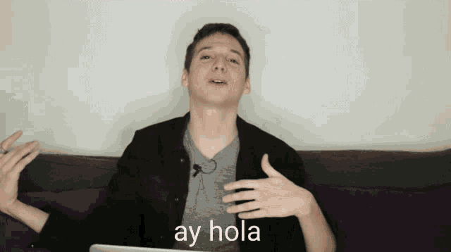 a man sitting on a couch with ay hola written on the bottom of his chest
