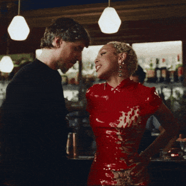 a man and a woman are standing next to each other in a bar