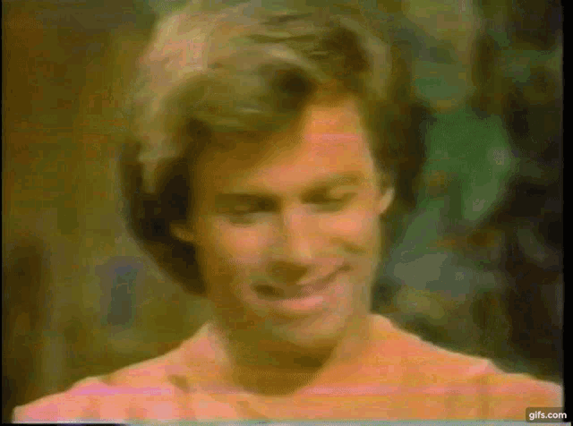 a close up of a man 's face with a pink shirt on