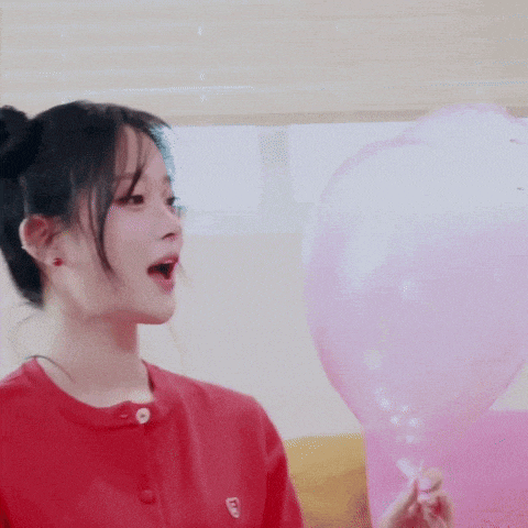 a woman wearing a red shirt with the letter e on it is holding a pink balloon