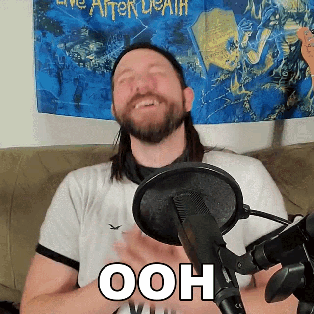 a man sitting in front of a microphone with the word ooh on his shirt