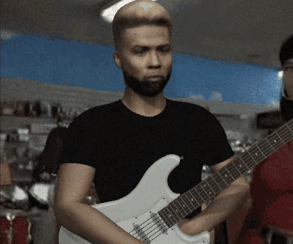 a man in a black shirt is playing a white electric guitar