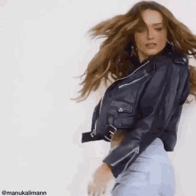 a woman wearing a leather jacket and jeans is dancing .