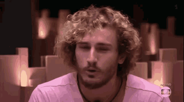 a man with curly hair and a beard wearing a pink shirt