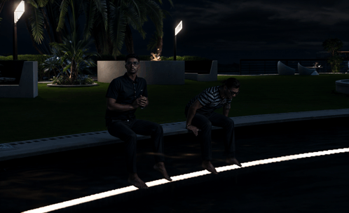 two men sit on a curb at night with a palm tree in the background