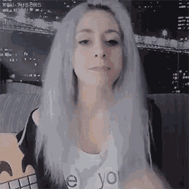 a woman with gray hair is sitting on a couch wearing a white shirt that says `` i love you '' .