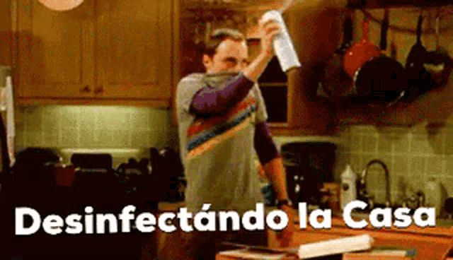 a man is spraying something in a kitchen with the words desinfectando la casa written below him .