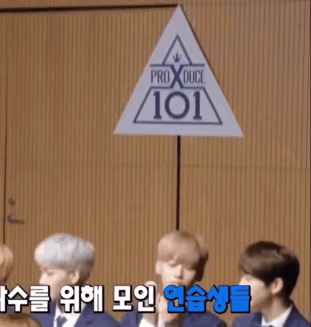 a group of people standing in front of a produce 101 sign