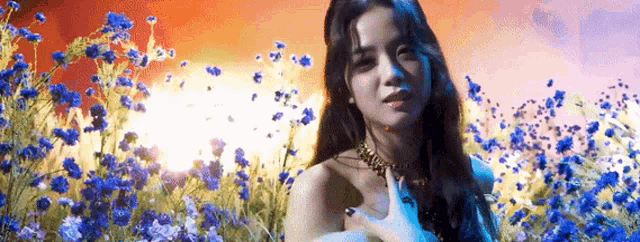 a woman is standing in a field of blue flowers and looking at the camera .