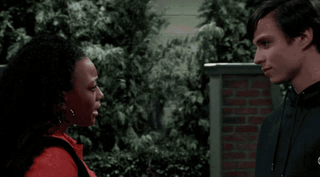 a man and a woman are looking at each other with trees in the background