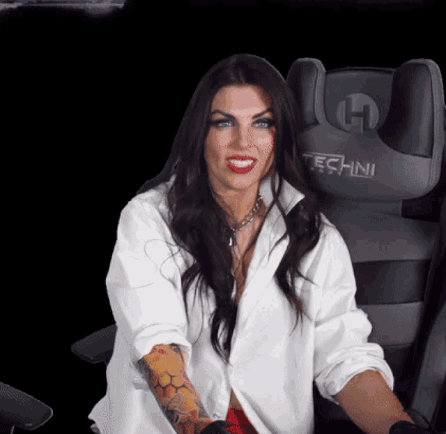 a woman in a white shirt is sitting in a techni gaming chair