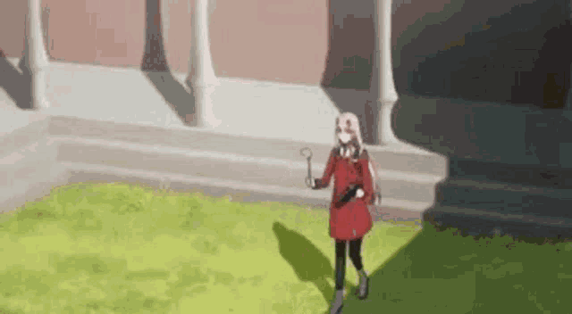 a girl in a red coat is holding a key in her hand while standing in a grassy area .