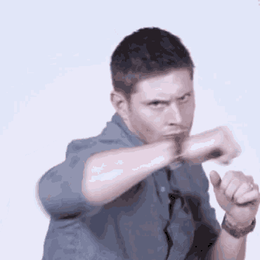 a man in a blue shirt is making a funny face while holding his fist in the air .