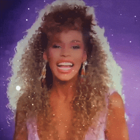 a woman with curly hair is smiling and wearing earrings