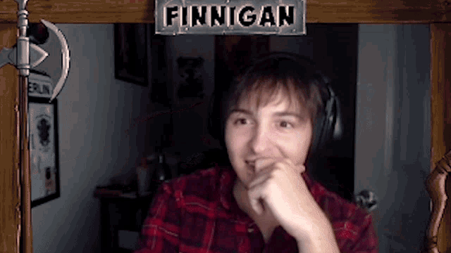 a man wearing headphones is sitting in front of a sign that says finnigan
