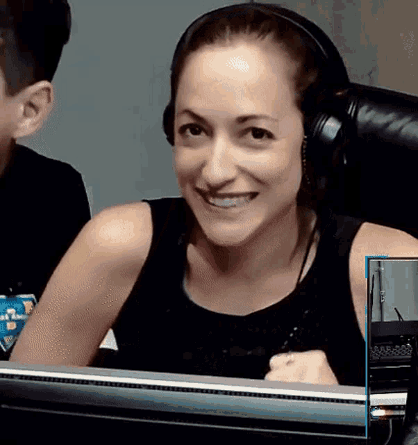 a woman wearing headphones is smiling while sitting in front of a computer screen