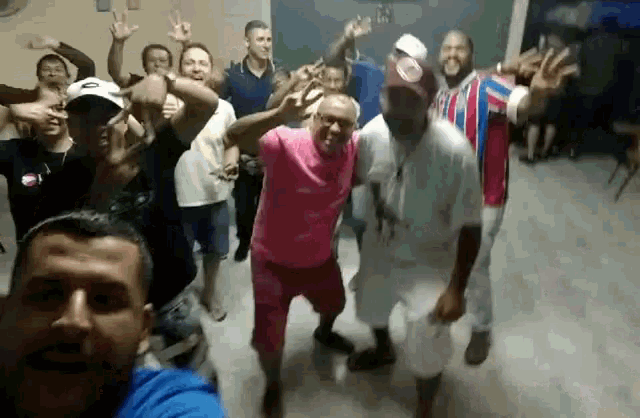 a group of people are dancing in a room and one of them is wearing a pink shirt