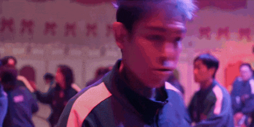 a man is standing in front of a crowd of people in a dark room with red lights .