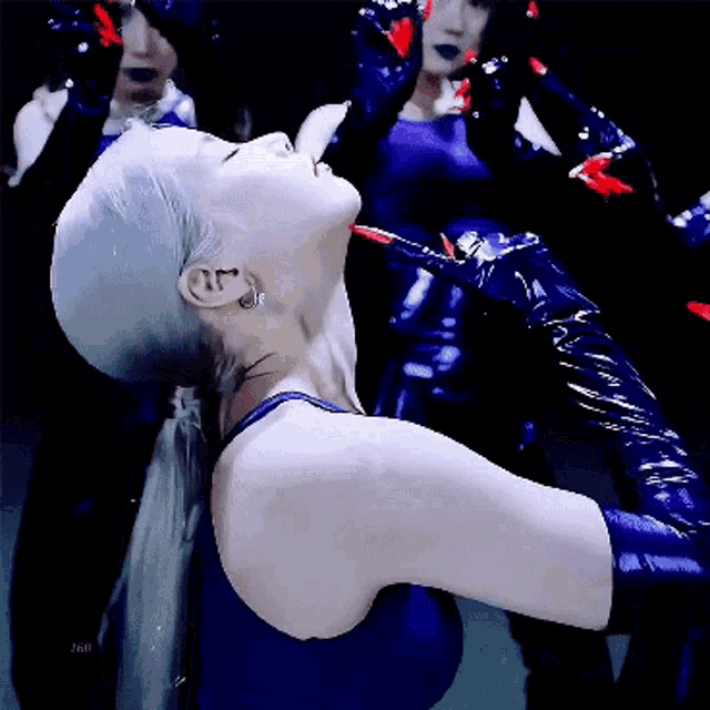 a woman in a blue top and gloves is dancing in front of a mirror