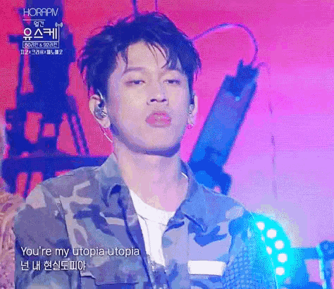 a young man wearing a camouflage jacket is singing a song on stage .