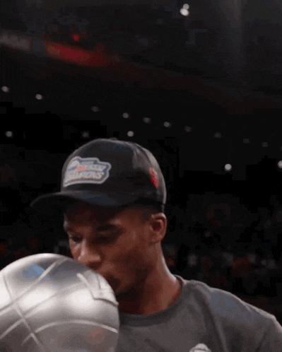 a man wearing a hat that says champions kisses a basketball