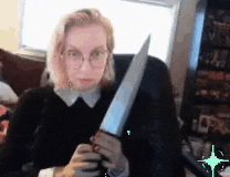 a woman is sitting in a chair holding a large knife in her hands .