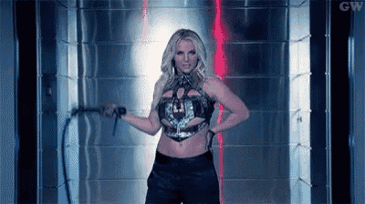 britney spears is holding a whip in her hand while standing in a room .