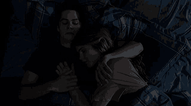 a man and a woman are sleeping in a bed together .