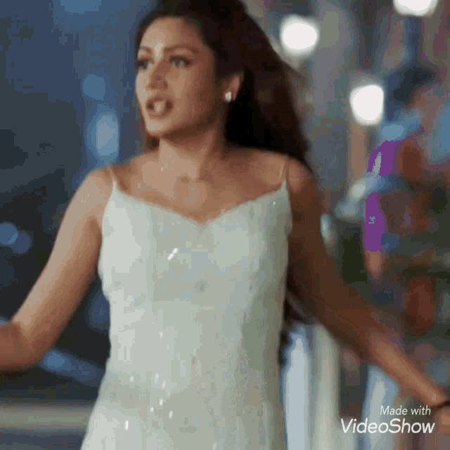 a woman in a white dress is walking down the street .