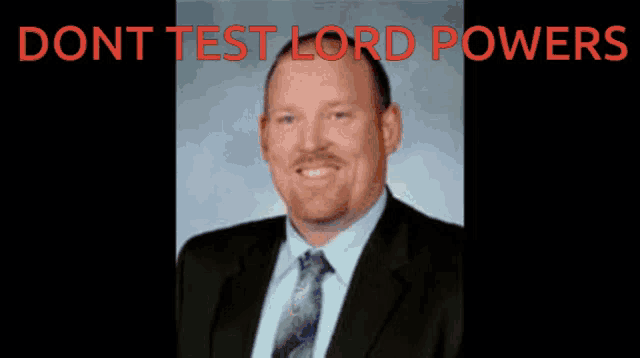 a man in a suit and tie stands in front of a brick building with the words " dont test lord powers "